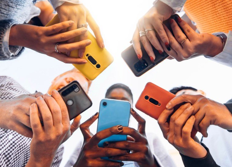 multicultural teenagers holding smartphones