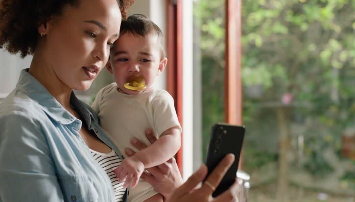 caregiver with smartphone and baby