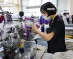 Cambodian worker operates Chinese embroidery machine at industrial expo